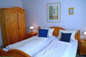 a bedroom with two beds with blue pillows at Haus 94- Whg EG in Oldsum