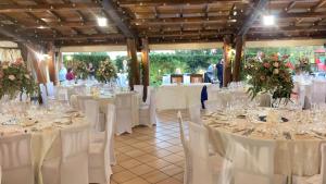 pokój pełen stołów z białymi krzesłami i kwiatami w obiekcie Agriturismo Podere Giulio w mieście Tarquinia