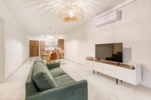 uma sala de estar com um sofá verde e uma televisão em A beautiful, brand new 2BR home in St Pauls by 360 Estates em St. Paul's Bay