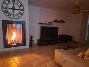 a living room with a fireplace and a clock on the wall at Villa de 2 à 10 personnes tarif en fonction du nombre de personnes in Vonnas