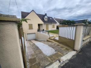 een wit huis met een poort en een garage bij Chambres dans Maison à Herblay sur seine in Herblay