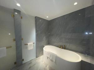 ドバイにあるLuxury Stay At Five Palm Residenceの白いバスタブとグレーの壁が備わるバスルーム +5枚の写真