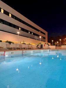 a large swimming pool in front of a building at night at NODIS MADRID POZUELO in Madrid