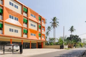 un edificio blanco y naranja con palmeras en el fondo en RedDoorz near GSG UNILA Lampung, en Hajimana