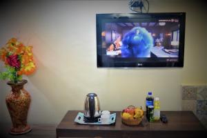 uma televisão pendurada numa parede com uma mesa com uma mesa em Hotel Star of Kashmir em Srinagar