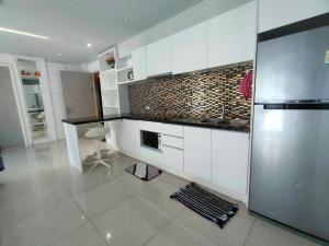 a kitchen with white cabinets and a stainless steel refrigerator at Seaview Atlantis Condo Resort Jomtien Beach Water Park in Jomtien Beach