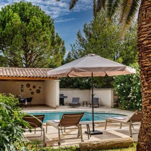 a patio with an umbrella and chairs and a pool at Maison Belleviste in Maillane