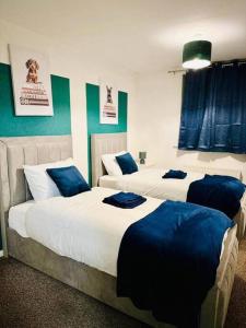 a bedroom with two beds with blue pillows on them at Beautiful House Sleeps 6 - Manchester in Manchester