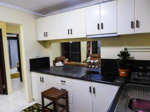 a kitchen with white cabinets and a black counter top at Yaubula Accommodation 2 in Nadi