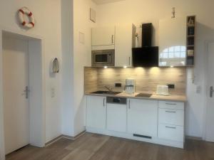 a kitchen with white cabinets and a counter top at Haus am Park - Wohnung 24 in Kühlungsborn