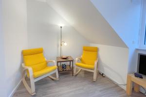 two yellow chairs in a room with a tv at Bernsteinquartier Ferienhaus 10a in Kolpinsee