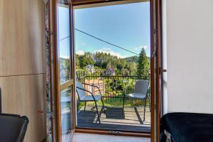 a room with a door open to a balcony with chairs at Willa Jolka - parking bezplatny, plac zabaw, wiata grillowa in Krynica Zdrój
