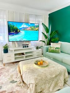 a living room with a tv and a couch at Luxury tropical 2bedroom apartment in resort 4 swimming pools in Cairns North