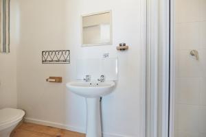 Un baño blanco con lavabo y ducha. en Chez Nous In Arniston, en Arniston