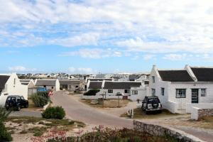 a village with two cars parked on a street at Dyers House Kassiesbaai Arniston in Arniston