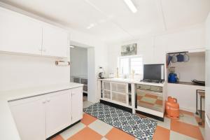 una cocina con armarios blancos y alfombra naranja en Cliff Cottage In Arniston, en Arniston