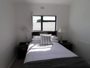 a bedroom with a large white bed with two lamps at Eland's Rest In Arniston in Arniston