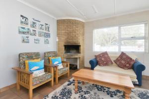a living room with a couch and chairs and a fireplace at Etna Flat In Arniston in Arniston