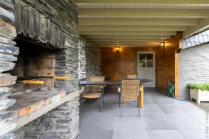 a patio with a table and chairs in a stone wall at Alhoumont - L'échappée ardennaise - Gîte rustique in Houffalize