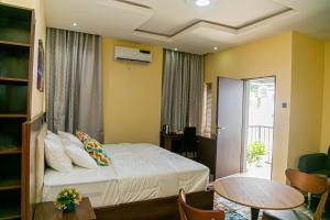 伊巴丹Fragrance Apartments and Suites的一间卧室配有一张床铺和一张桌子,并设有一个阳台