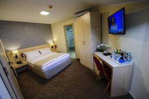 a hotel room with a bed and a television on the wall at Pensiunea President City in Roşiori de Vede