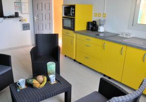 a kitchen with yellow cabinets and a table with a bowl of fruit at Le Gîte Des Plantations in Capesterre-Belle-Eau