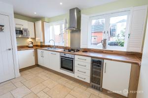 uma cozinha com armários brancos e uma bancada em Tranquil 3-Bedroom Haven in Lymington - The Herons Nest em Lymington