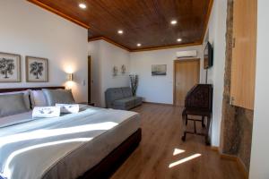 オリヴェイラ・デ・フラデスにあるQuinta das Mirandas Natureの大きなベッドと椅子が備わるホテルルームです。