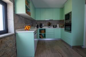 a kitchen with green cabinets and a counter with oranges on it at Quinta das Mirandas Nature in Oliveira de Frades