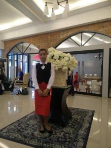 una mujer parada en una habitación con un jarrón de flores en Oval era mall hotel condo suites, en Bangued