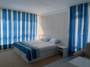 Schlafzimmer mit einem Bett und blauen Vorhängen in der Unterkunft STELA in Nessebar
