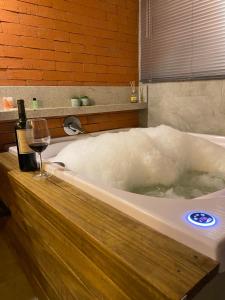 bañera con botella de vino y copa en Cabana I com Banheira Hidro e Lareira - Chalet Mont Blanc - Urubici, en Urubici 40 fotos más