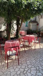 a group of red tables and chairs under a tree at Dody Apartmani in Leskovac