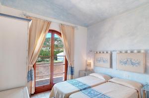 a bedroom with two beds and a large window at Le Residenze di Piazza Italia in Costa Rei