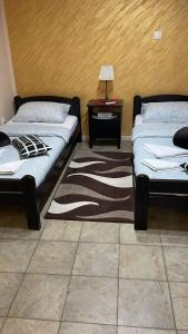 a room with two beds and a table with a rug at Dody Apartmani in Leskovac