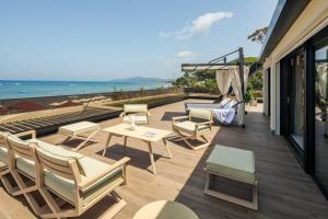 patio z krzesłami i stołami oraz widokiem na ocean w obiekcie Cala Beach Resort w mieście Punta Ala