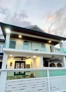 a white house with a balcony in front of it at Three Homestay in Perai