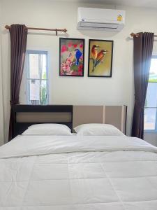 a bedroom with a bed and three paintings on the wall at PICHAPON RESORT in Pak Chong