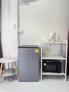 a refrigerator next to a microwave next to a stool at PICHAPON RESORT in Pak Chong