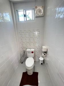 a white bathroom with a toilet and a window at PICHAPON RESORT in Pak Chong