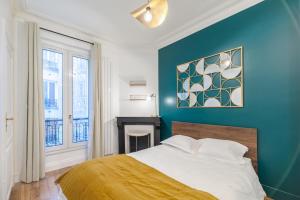 a bedroom with a bed and a blue wall at Bridgestreet - Opera Montmartre in Paris