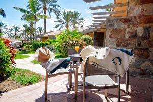 a patio with two chairs and a table with a wine glass at Suites & Villas by Dunas in Maspalomas