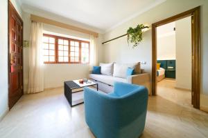 a living room with a blue chair and a couch at Suites & Villas by Dunas in Maspalomas
