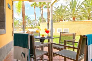 a table and chairs on a patio with palm trees at Suites & Villas by Dunas in Maspalomas