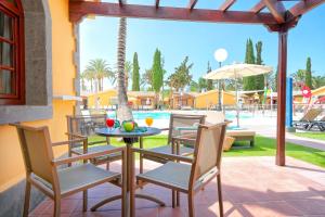 a patio with a table and chairs and a pool at Suites & Villas by Dunas in Maspalomas