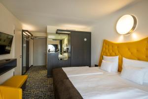 une chambre d'hôtel avec un grand lit avec une tête de lit jaune dans l'établissement ARCOTEL Onyx Hamburg, à Hambourg