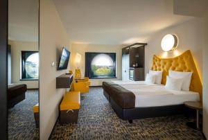 um quarto de hotel com uma cama grande e um espelho em ARCOTEL Onyx Hamburg em Hamburgo