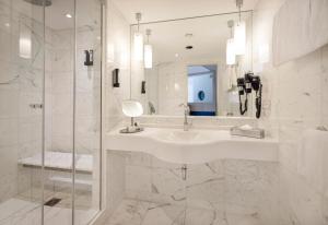 a white bathroom with a sink and a mirror at ARCOTEL Onyx Hamburg in Hamburg