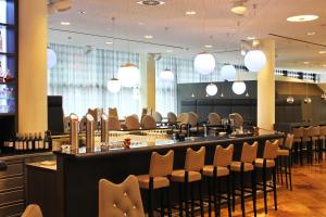 a restaurant with a bar with chairs and lights at ARCOTEL Onyx Hamburg in Hamburg