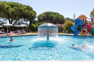 two people in a swimming pool with a water fountain at Gitavillage Argentario in Albinia
